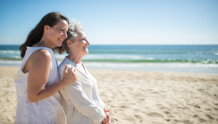 Fotografía para artículo de blog topfarma sobre la vitamina D. En la foto vemos a una mujer y a su madre, de pié frente al mar, disfrutando del sol.